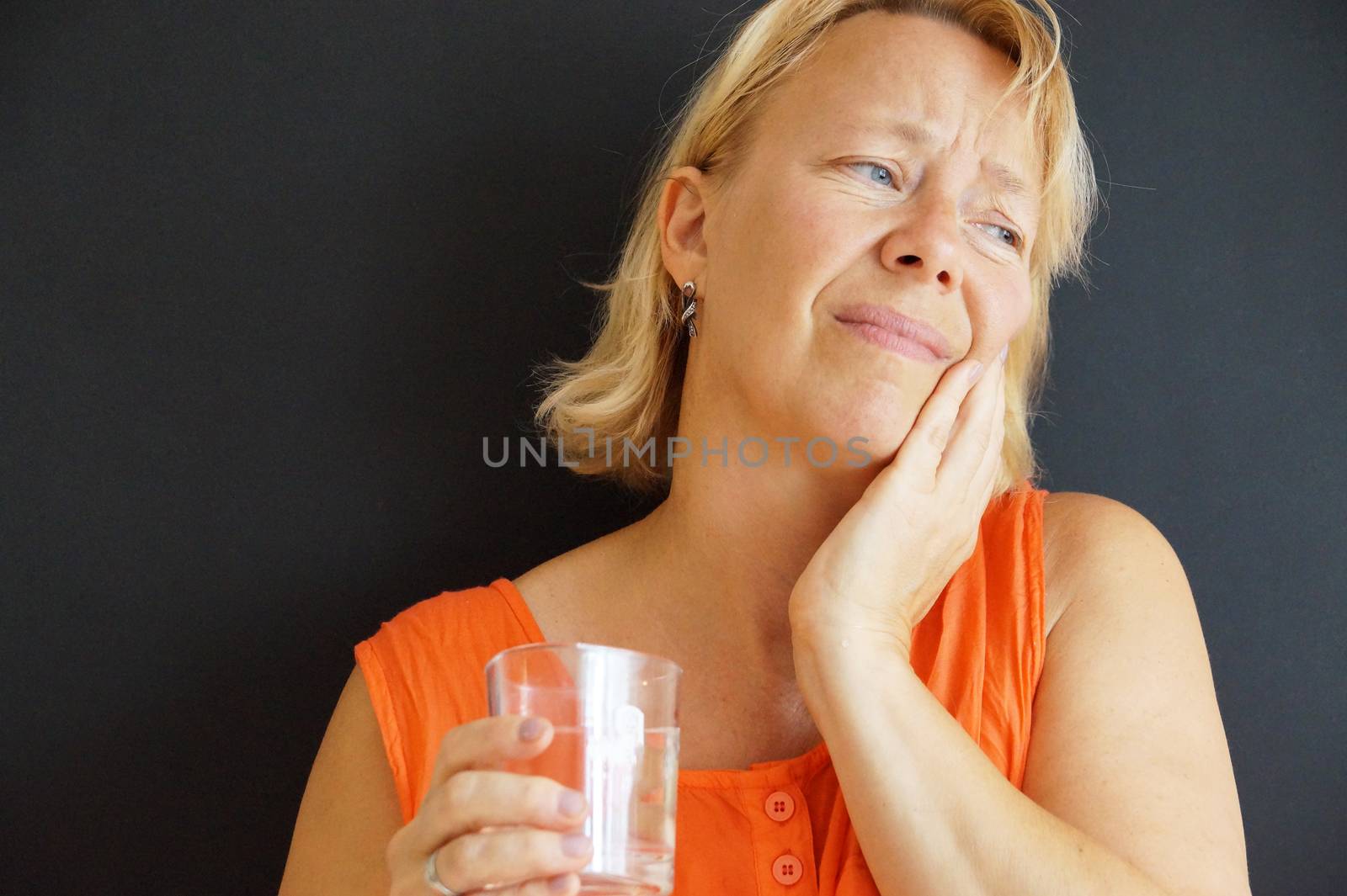 upset woman holding her bad tooth with her hand by Annado