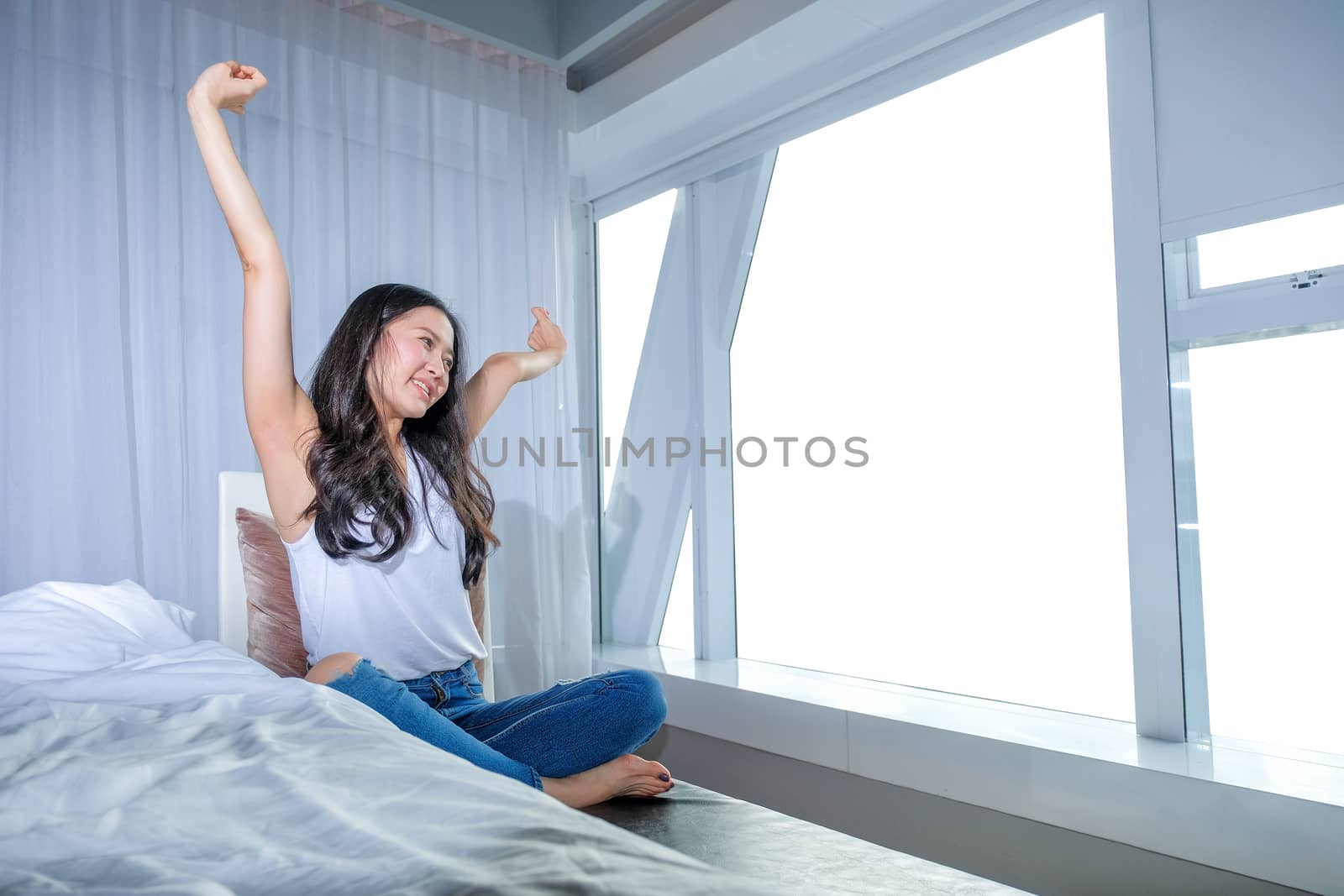 Woman stretch herself out after waking up in the morning on whit by Surasak