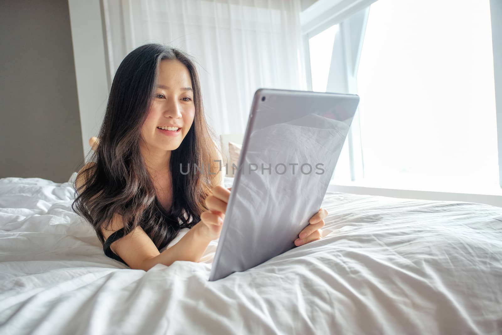 Yound woman using tablet on the bed  by Surasak