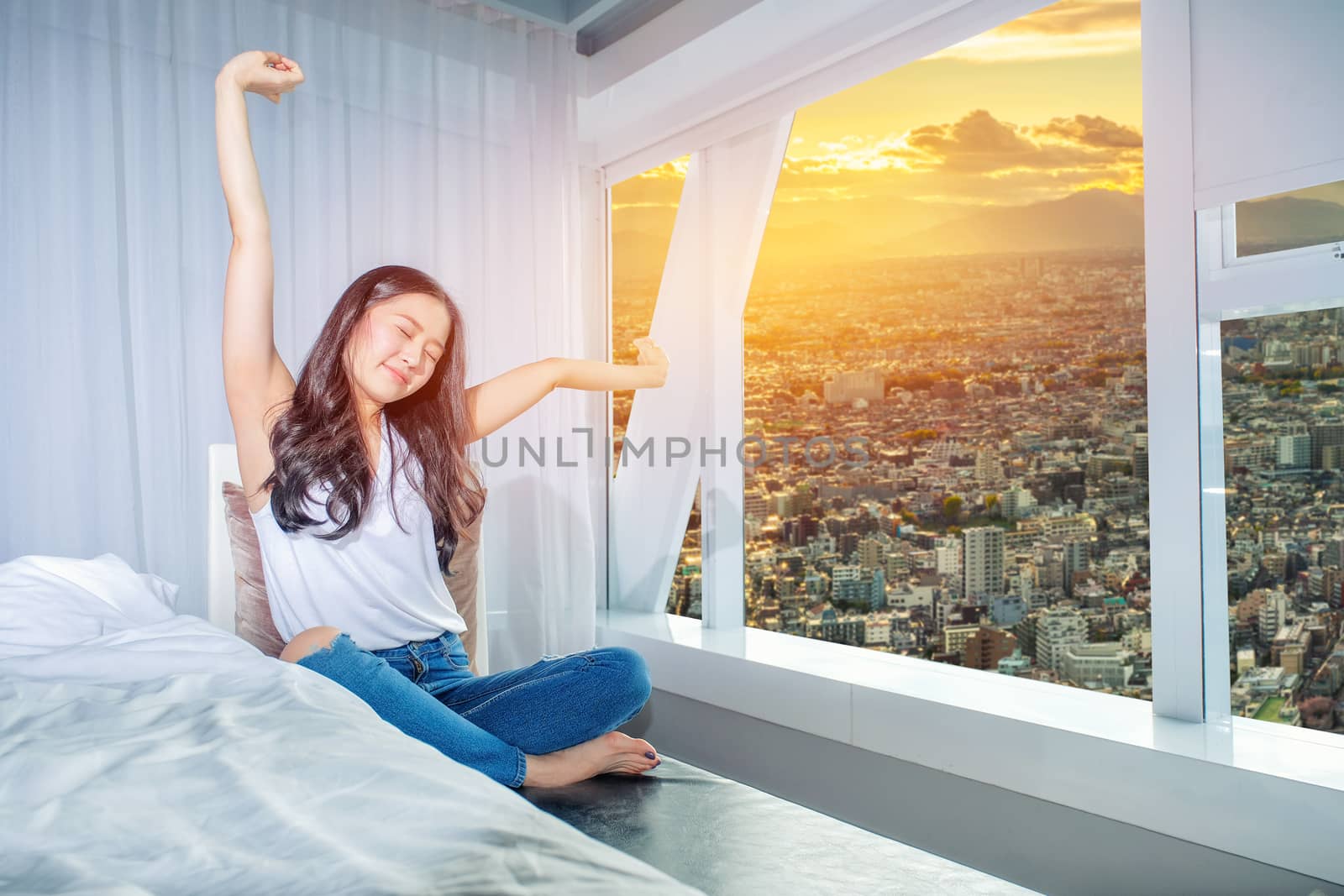 Woman stretch herself out after waking up in the morning on whit by Surasak