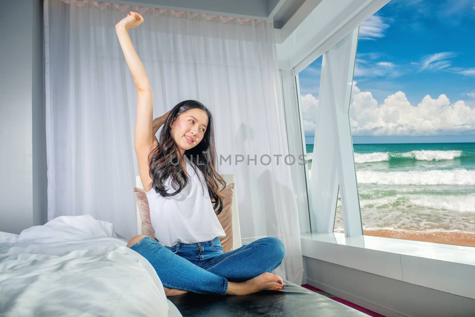 Woman stretch herself out after waking up in the morning on whit by Surasak