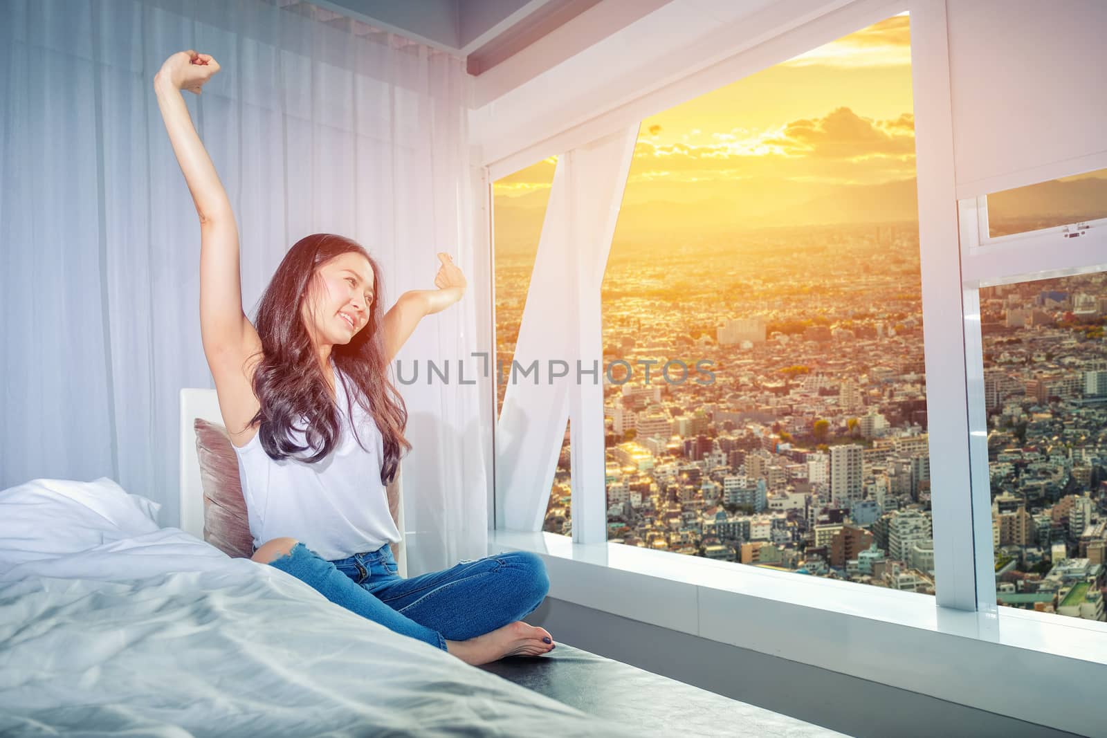 Woman stretch herself out after waking up in the morning on whit by Surasak