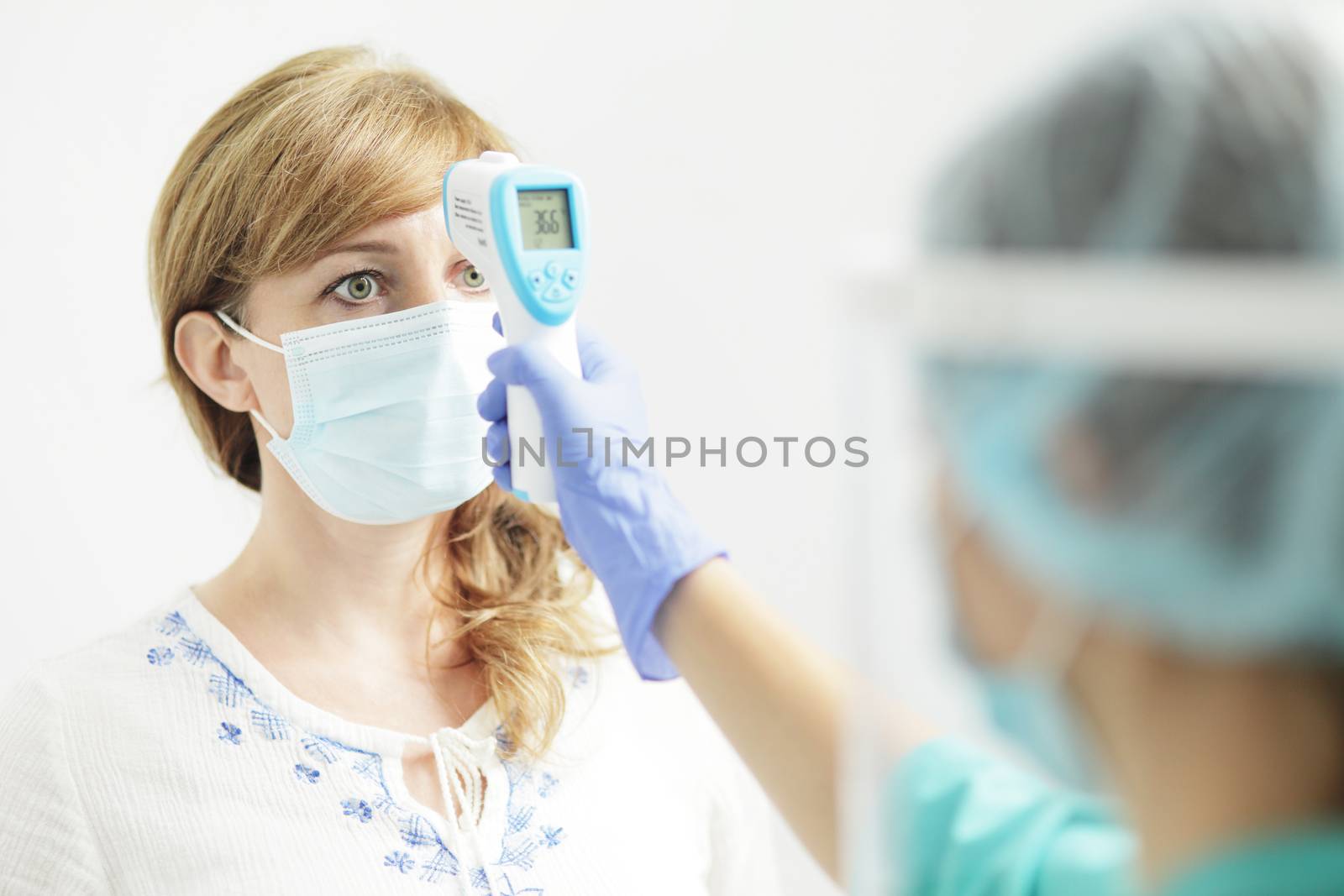 Medical woman in uniform measures the temperature of a woman with a pyrometer by selinsmo