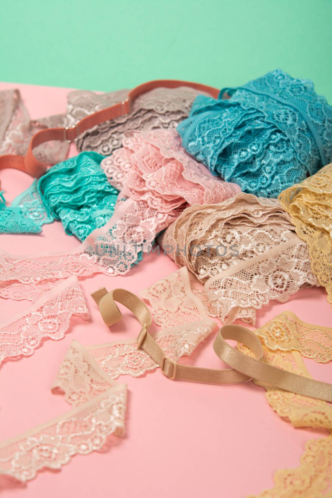 Abstract background with pile of color lace for Lingerie, panties, and bras on pink background. by polyats