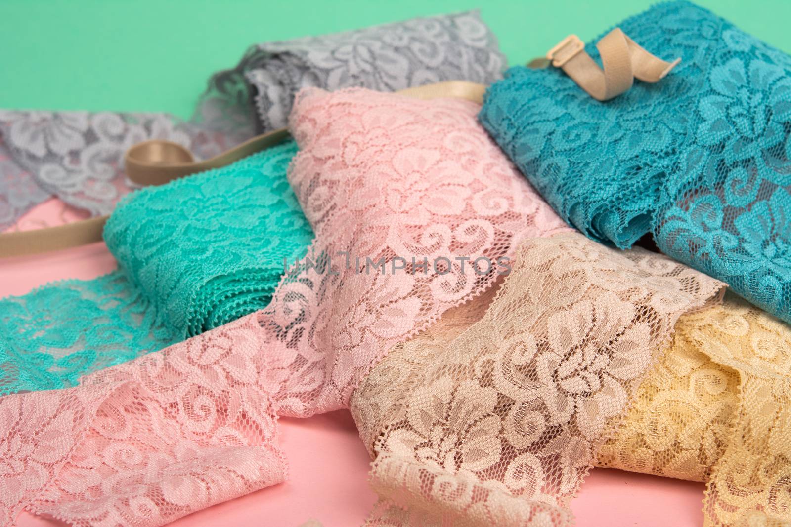 Abstract background with pile of color lace for Lingerie, panties, and bras on pink background. Delicate sophisticated glamorous elastic material. Using for Atelier and fabric store.