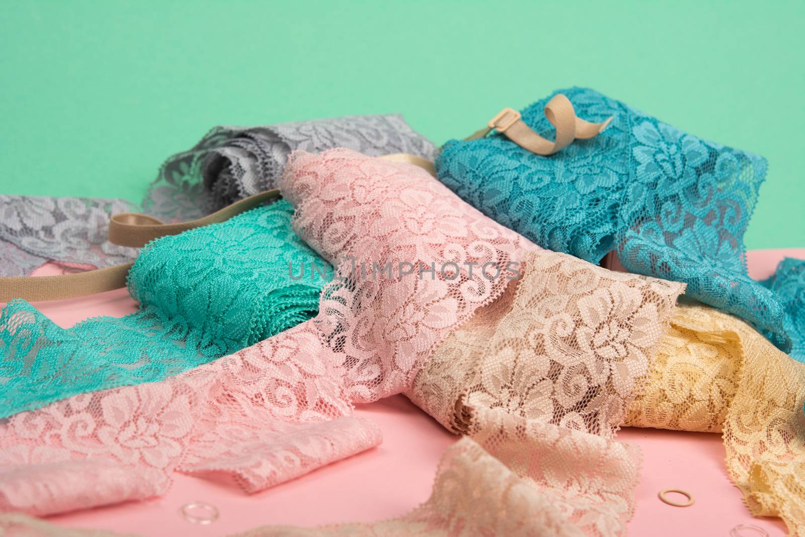 Abstract background with pile of color lace for Lingerie, panties, and bras on pink background. Delicate sophisticated glamorous elastic material. Using for Atelier and fabric store.