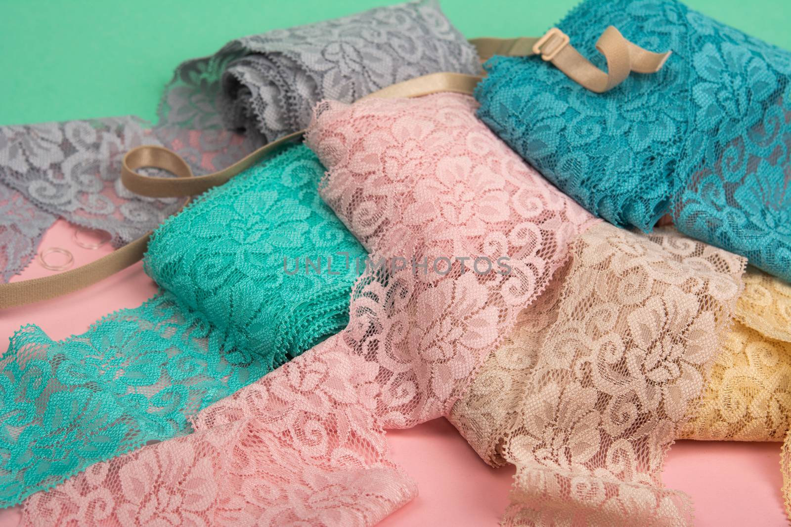 Abstract background with pile of color lace for Lingerie, panties, and bras on pink background. Delicate sophisticated glamorous elastic material. Using for Atelier and fabric store.