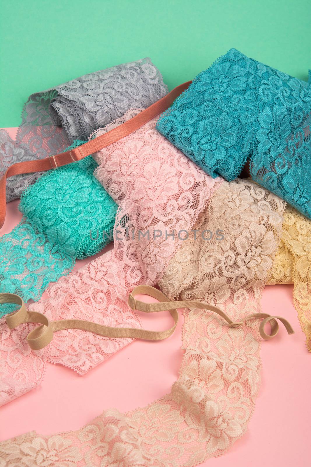 Abstract background with pile of color lace for Lingerie, panties, and bras on pink background. Delicate sophisticated glamorous elastic material. Using for Atelier and fabric store.