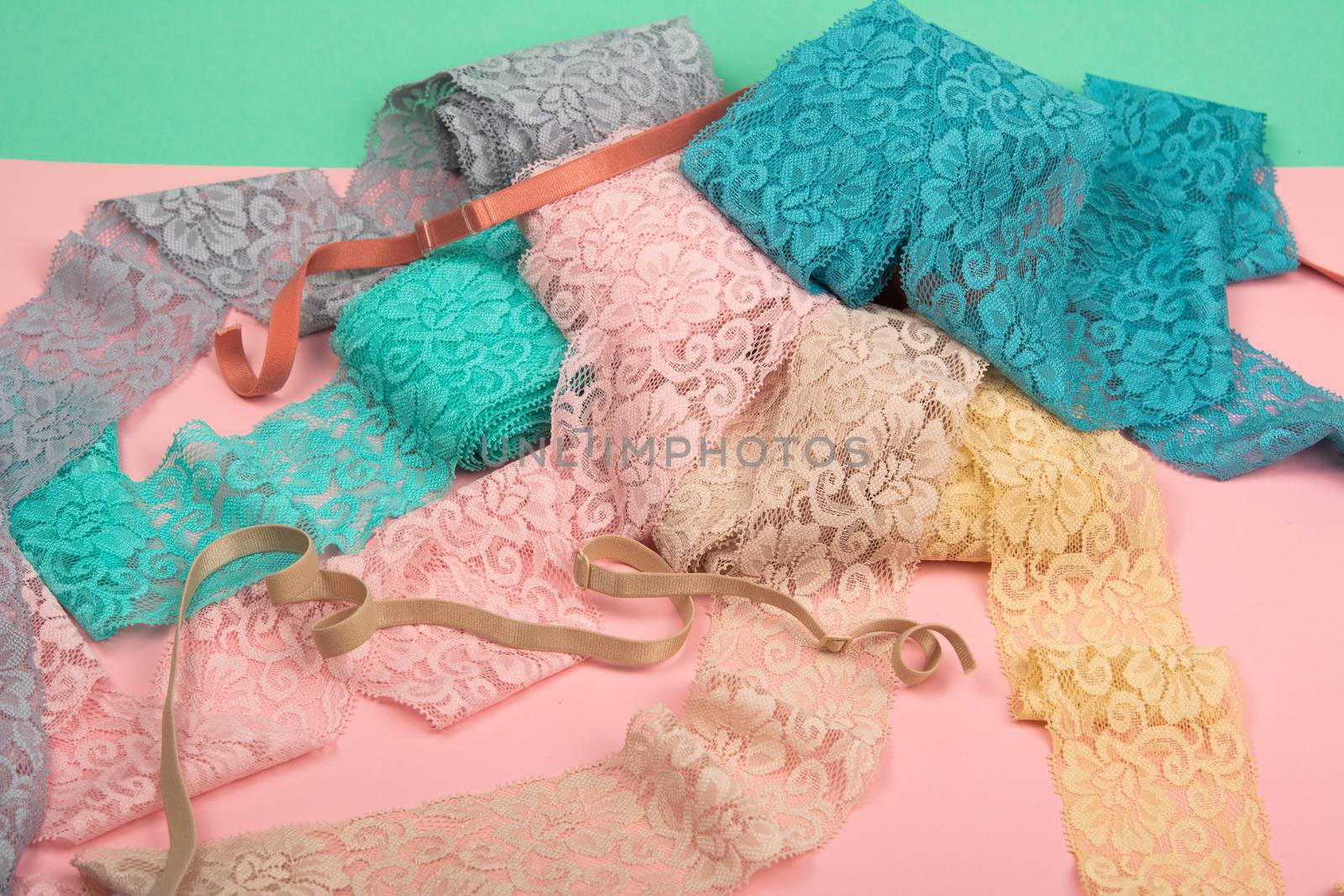 Abstract background with pile of color lace for Lingerie, panties, and bras on pink background. Delicate sophisticated glamorous elastic material. Using for Atelier and fabric store.