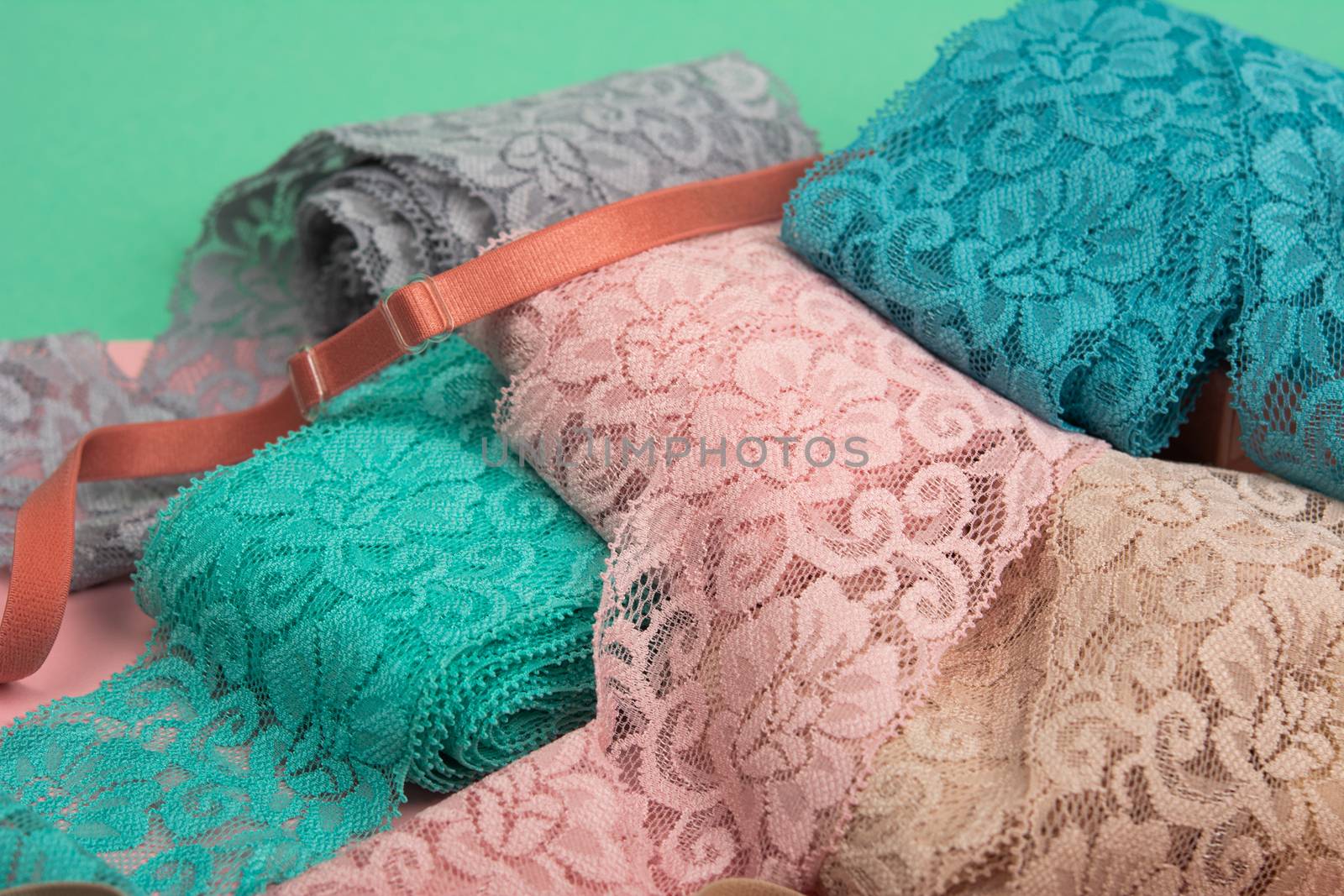 Abstract background with pile of color lace for Lingerie, panties, and bras on pink background. Delicate sophisticated glamorous elastic material. Using for Atelier and fabric store.