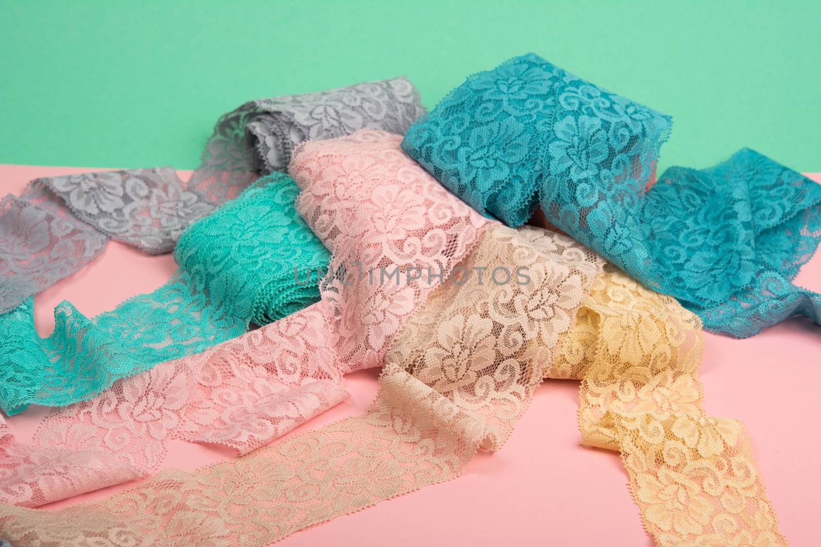 Abstract background with pile of color lace for Lingerie, panties, and bras on pink background. Delicate sophisticated glamorous elastic material. Using for Atelier and fabric store.