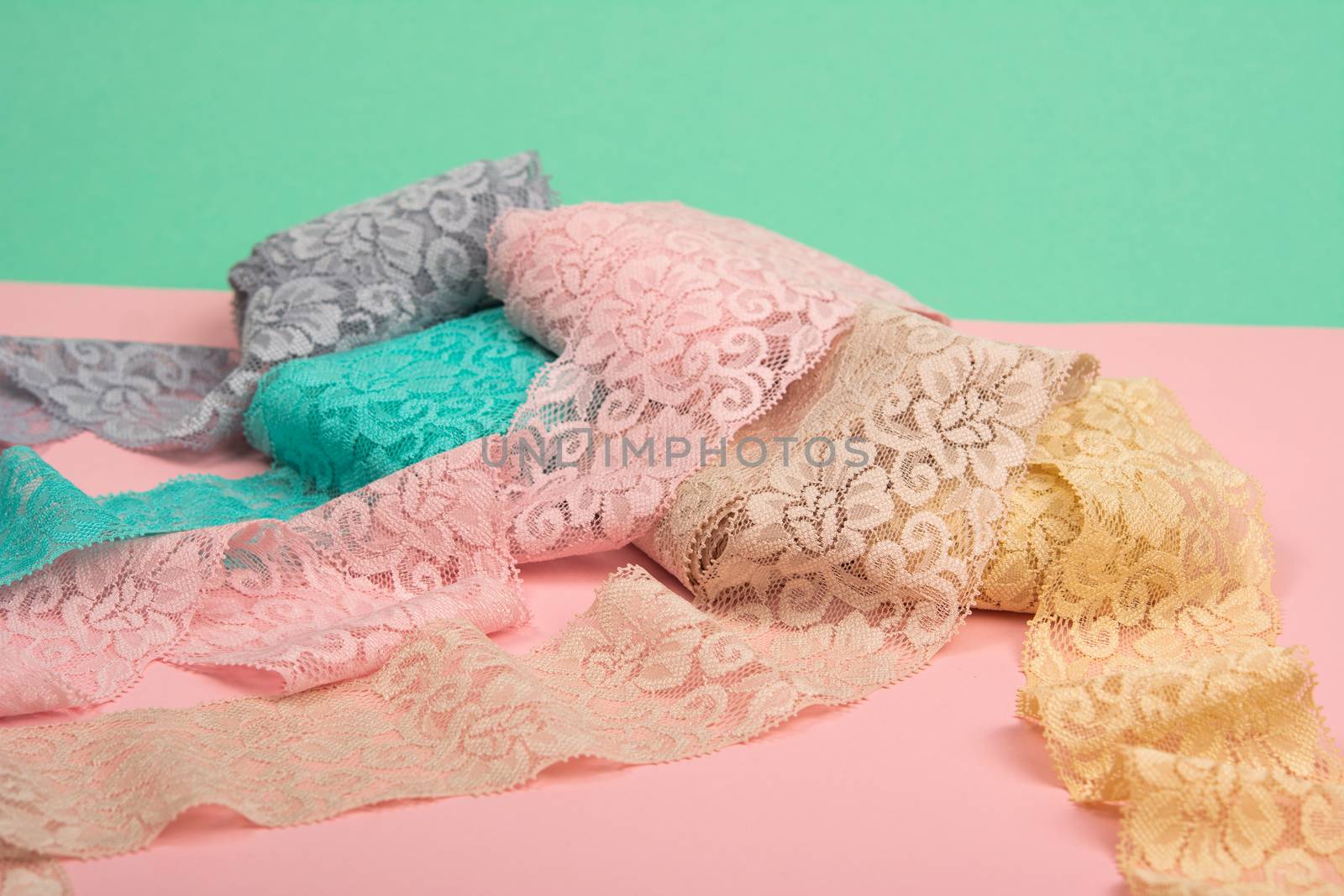 Abstract background with pile of color lace for Lingerie, panties, and bras on pink background. Delicate sophisticated glamorous elastic material. Using for Atelier and fabric store.