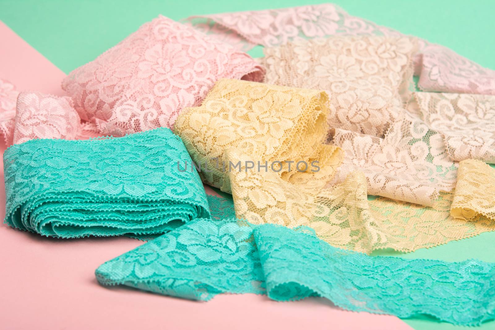 Abstract background with pile of color lace for Lingerie, panties, and bras on pink background. Delicate sophisticated glamorous elastic material. Using for Atelier and fabric store.