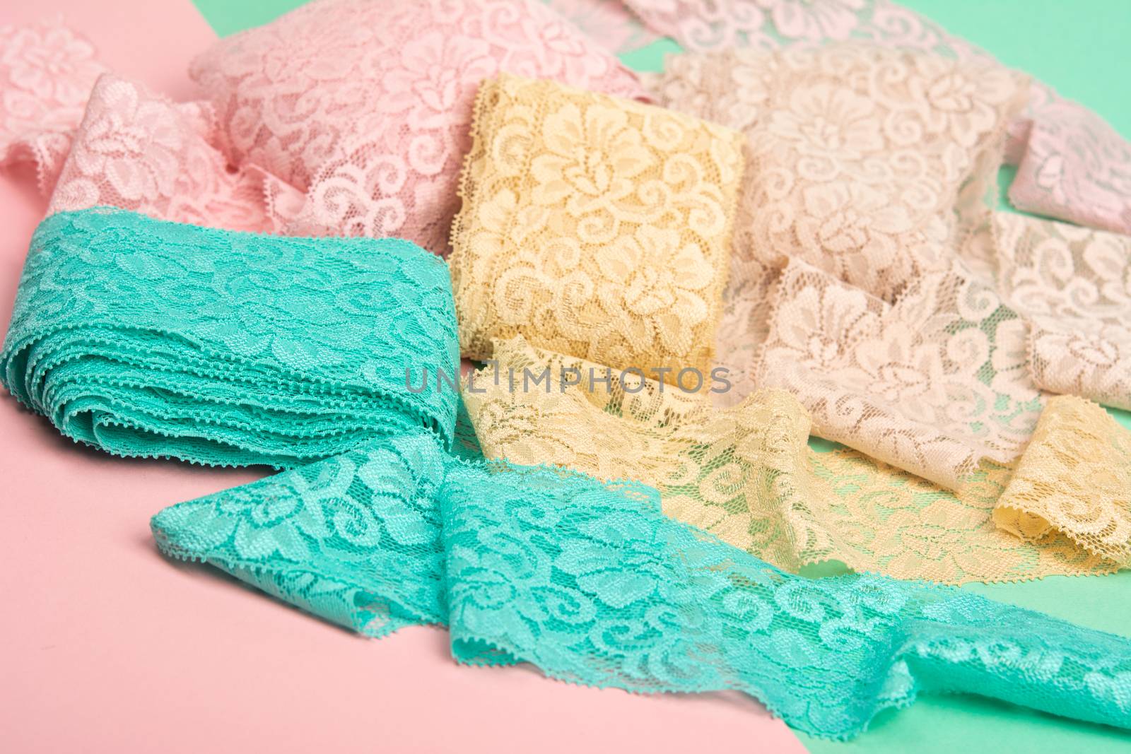 Abstract background with pile of color lace for Lingerie, panties, and bras on pink background. Delicate sophisticated glamorous elastic material. Using for Atelier and fabric store.