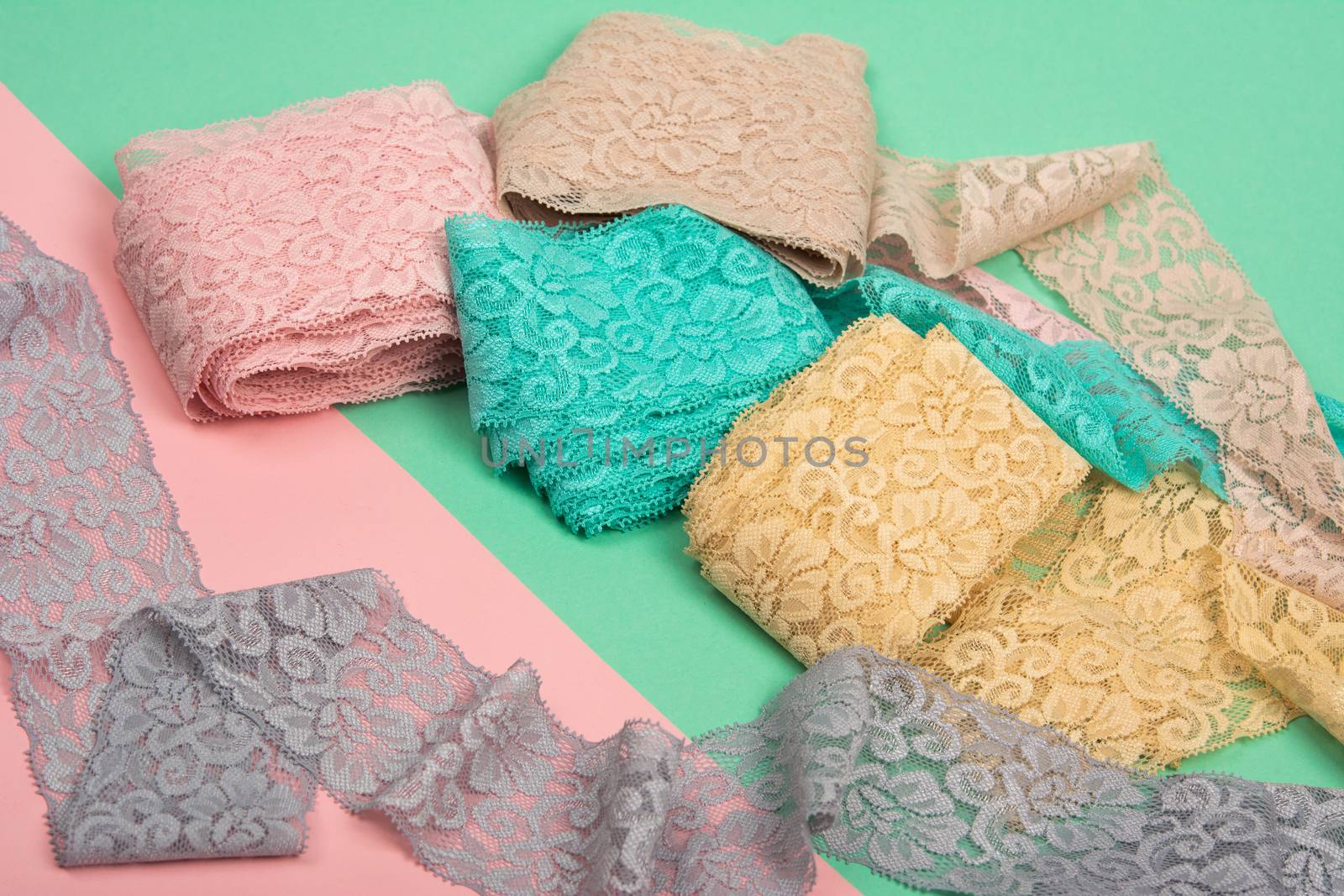 Abstract background with pile of color lace for Lingerie, panties, and bras on pink background. Delicate sophisticated glamorous elastic material. Using for Atelier and fabric store.