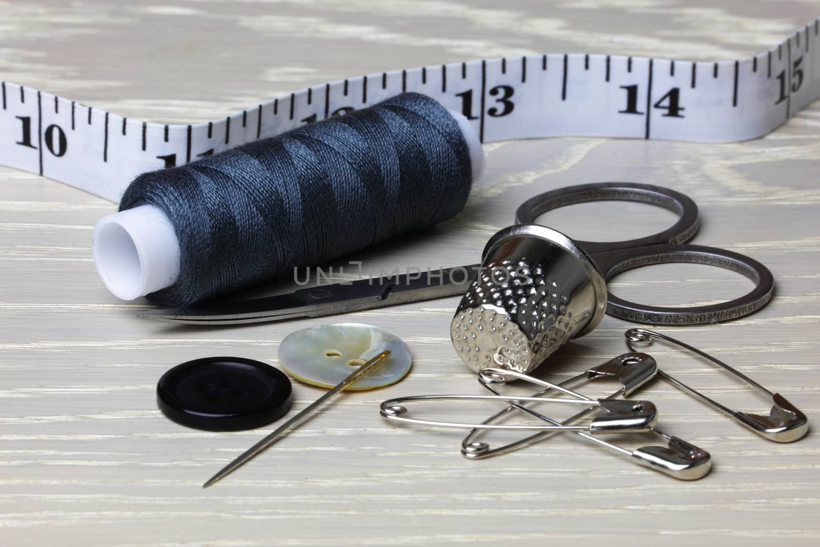 Supplies and equipment for sewing on wood work surface cotton tape measure scissors thimble needle pins buttons