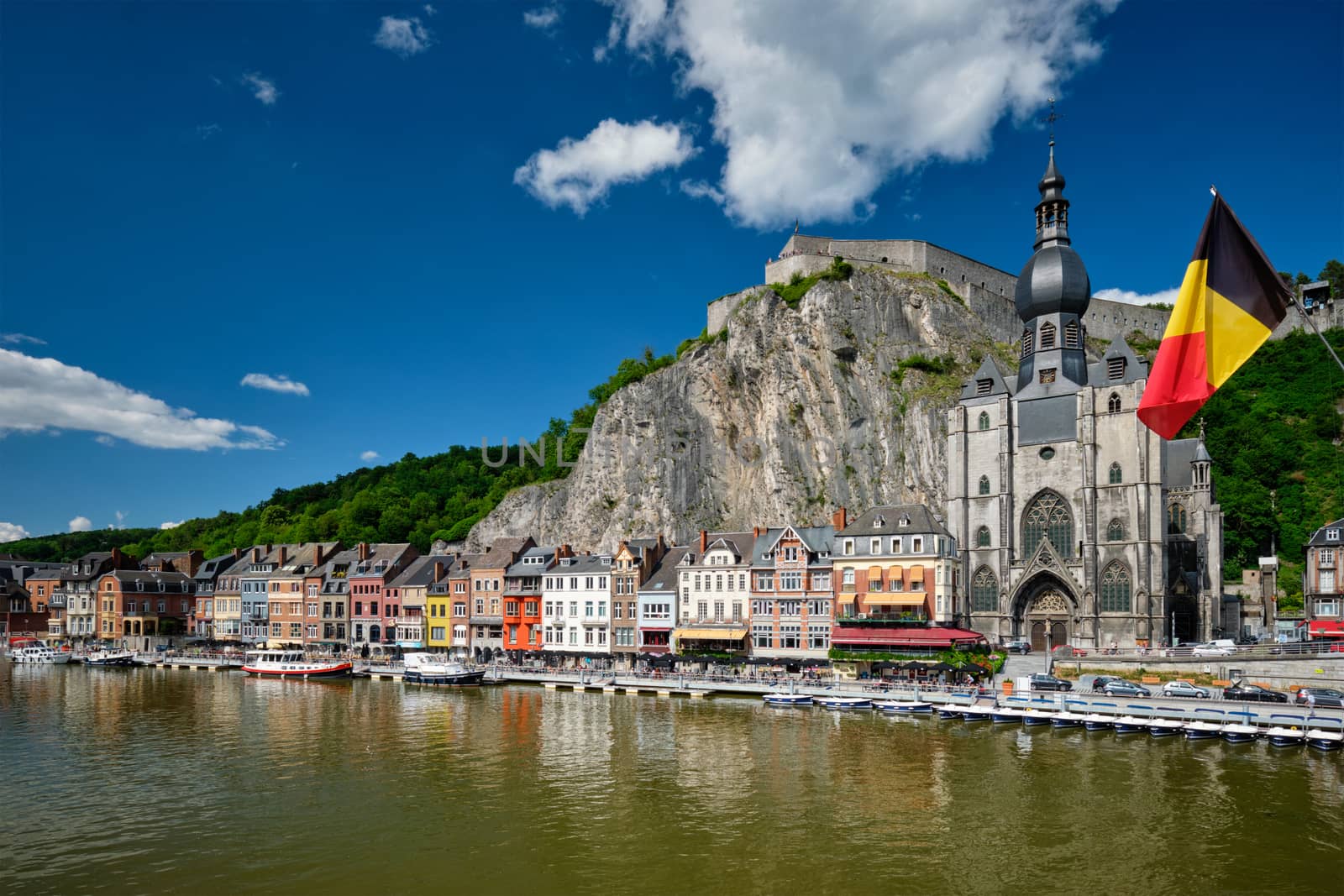 View of picturesque Dinant town, Dinant Citadel and Collegiate Church of Notre Dame de Dinant over the Meuse river with belgium flag. Belgian province of Namur, Blegium