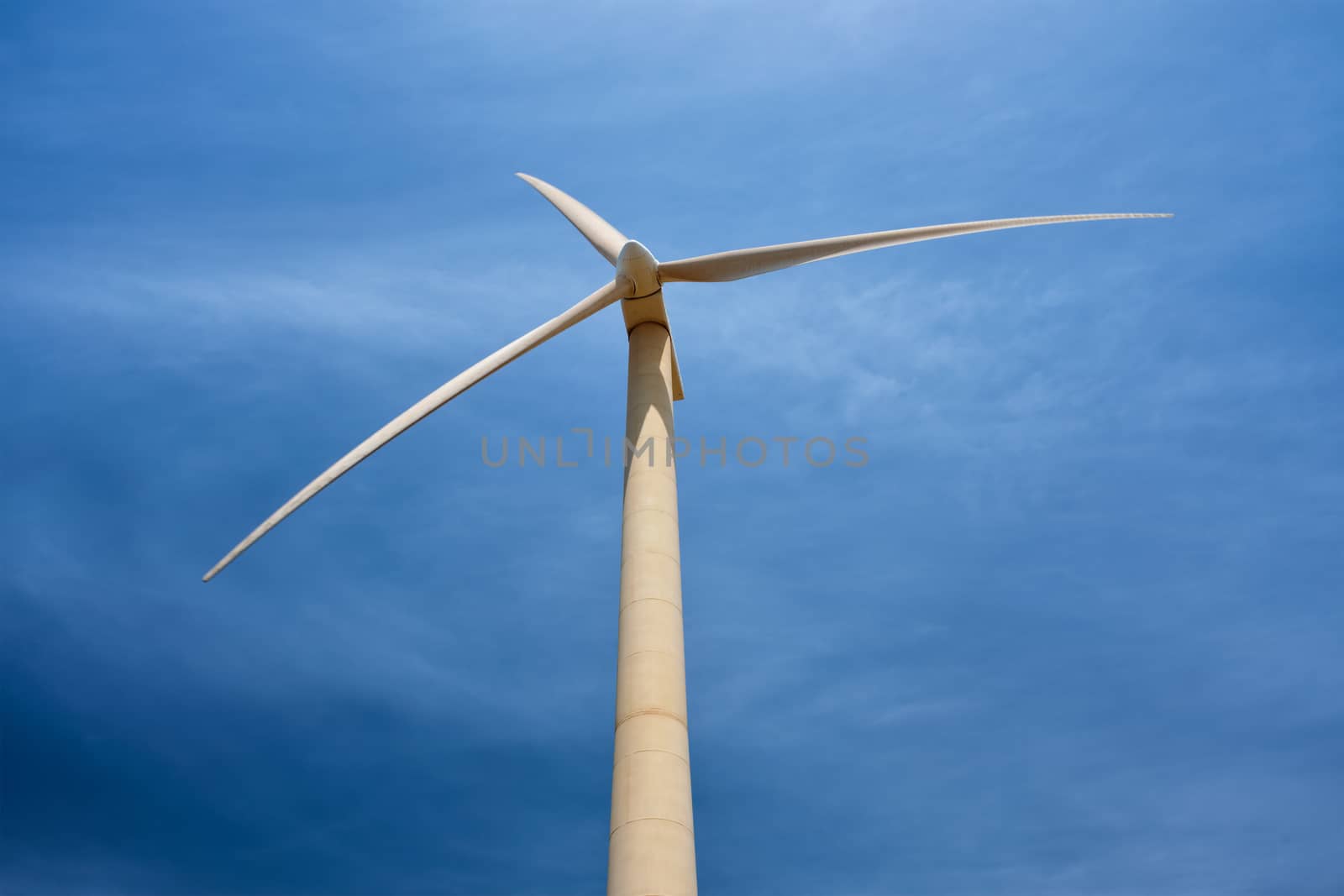 Green renewable alternative energy concept - wind generator turbine generating electricity in blue sky