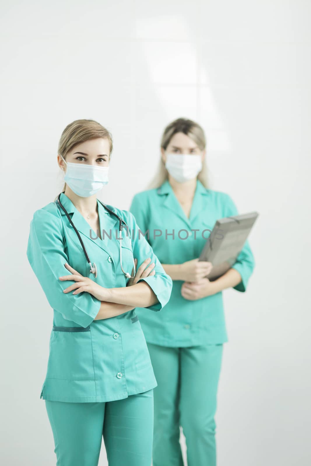 Two female doctor or nurse wearing medical masks looking at the camera. Stethoscope phonendoscope on the neck