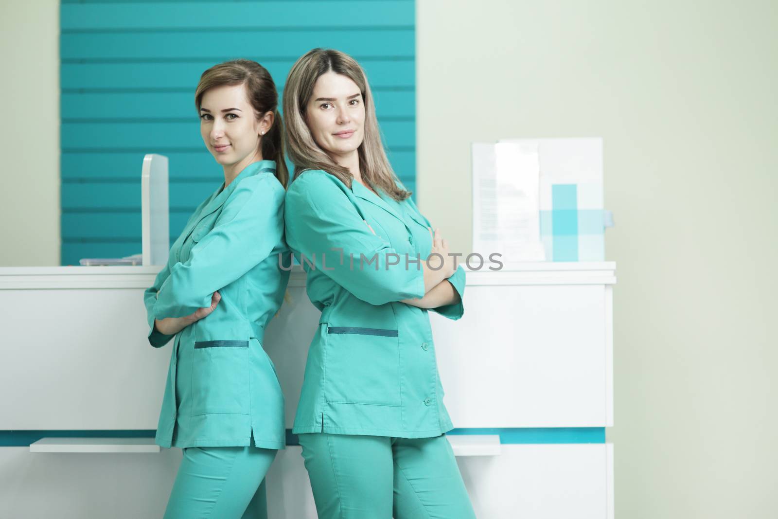 Two female doctors or nurses looking at the camera. In the hospital reception by selinsmo