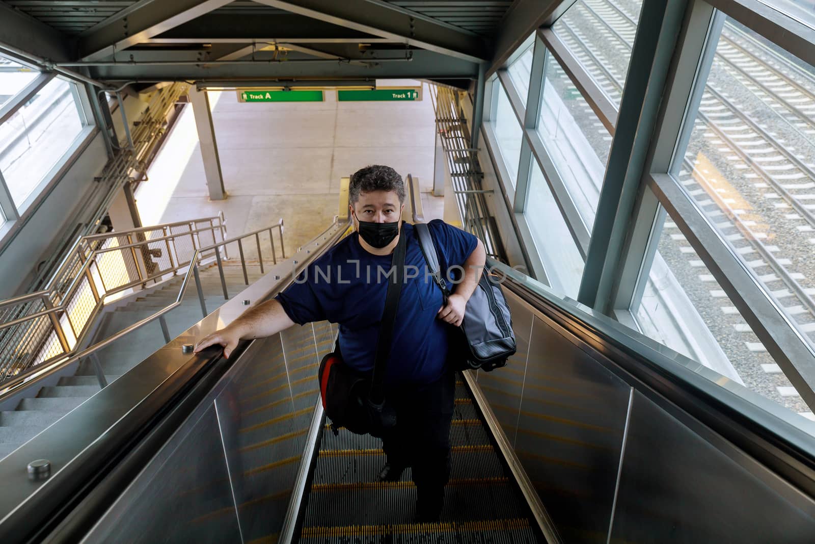 Traveling during the pandemic man wearing protective face mask on standing on an escalator the railway station