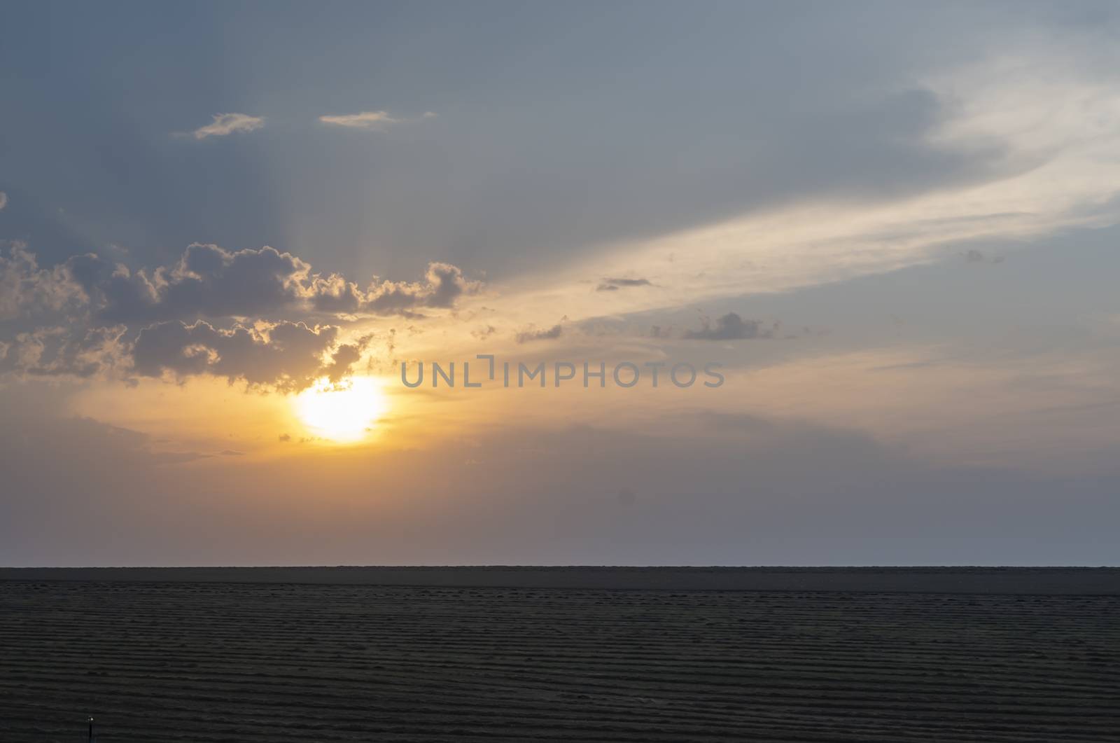 dark landscape of evening cloudy sunset on the background of an agricultural field
