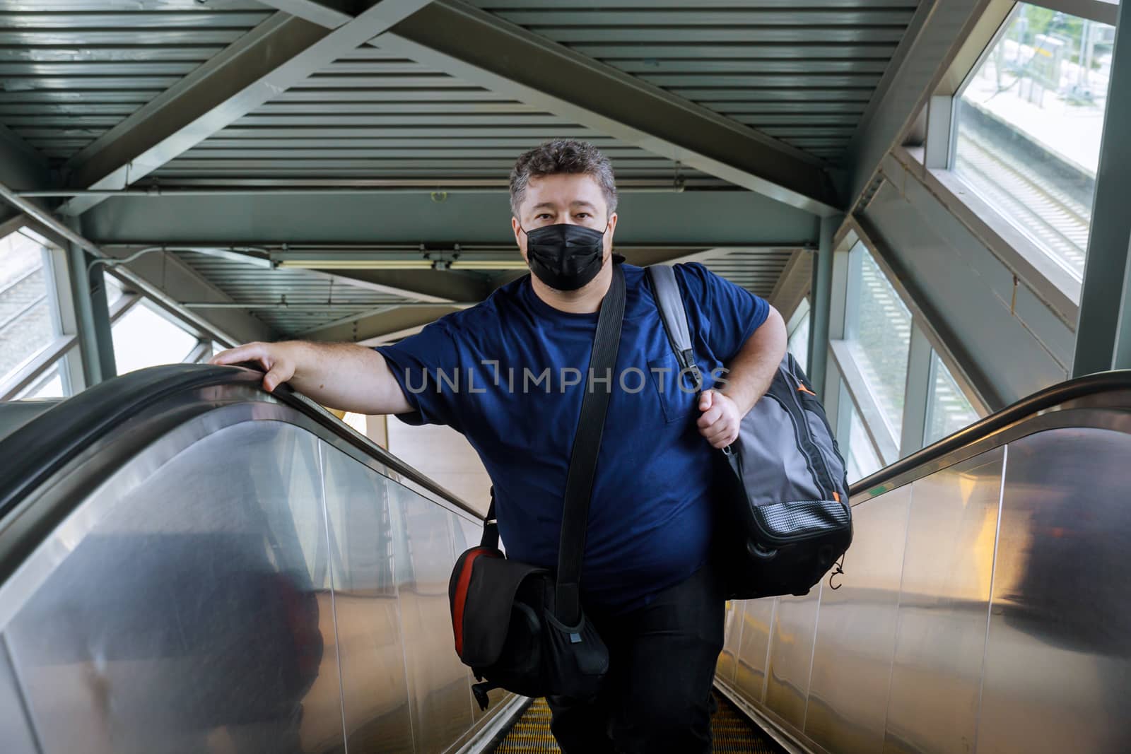 Man wear surgical face mask for protecting coronavirus, stand on the escalator, travel to the train, for trip during pandemic COVID-19