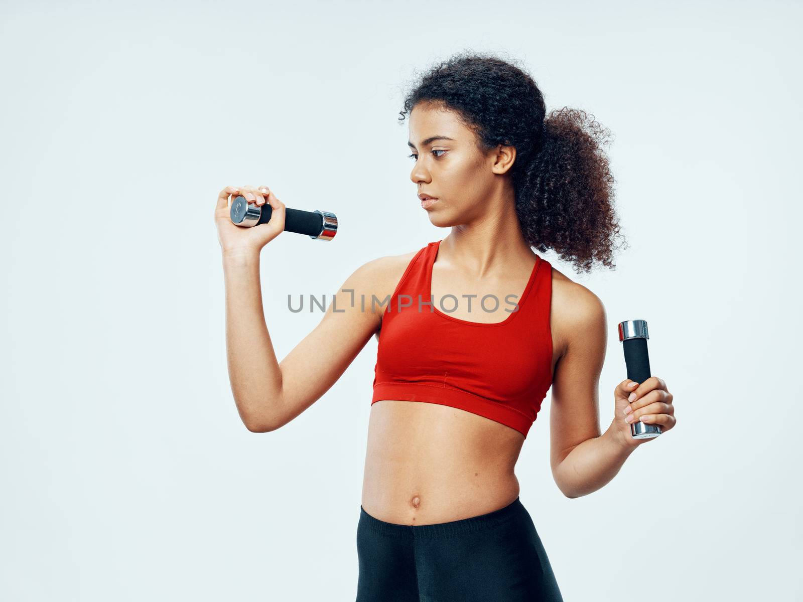 Sporty woman with dumbbells in hands doing exercises motivation workout in gym