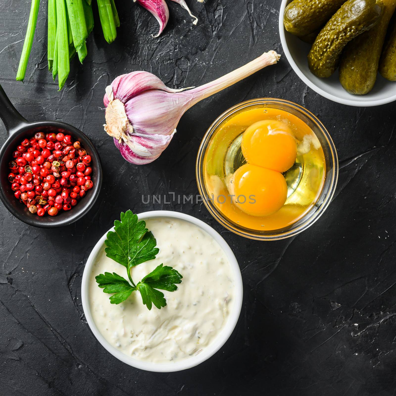 Homemade white sauce tartar tartare with ingredients pickles, capers, dill, parsley, garlic, lemon on black stone table top view square by Ilianesolenyi