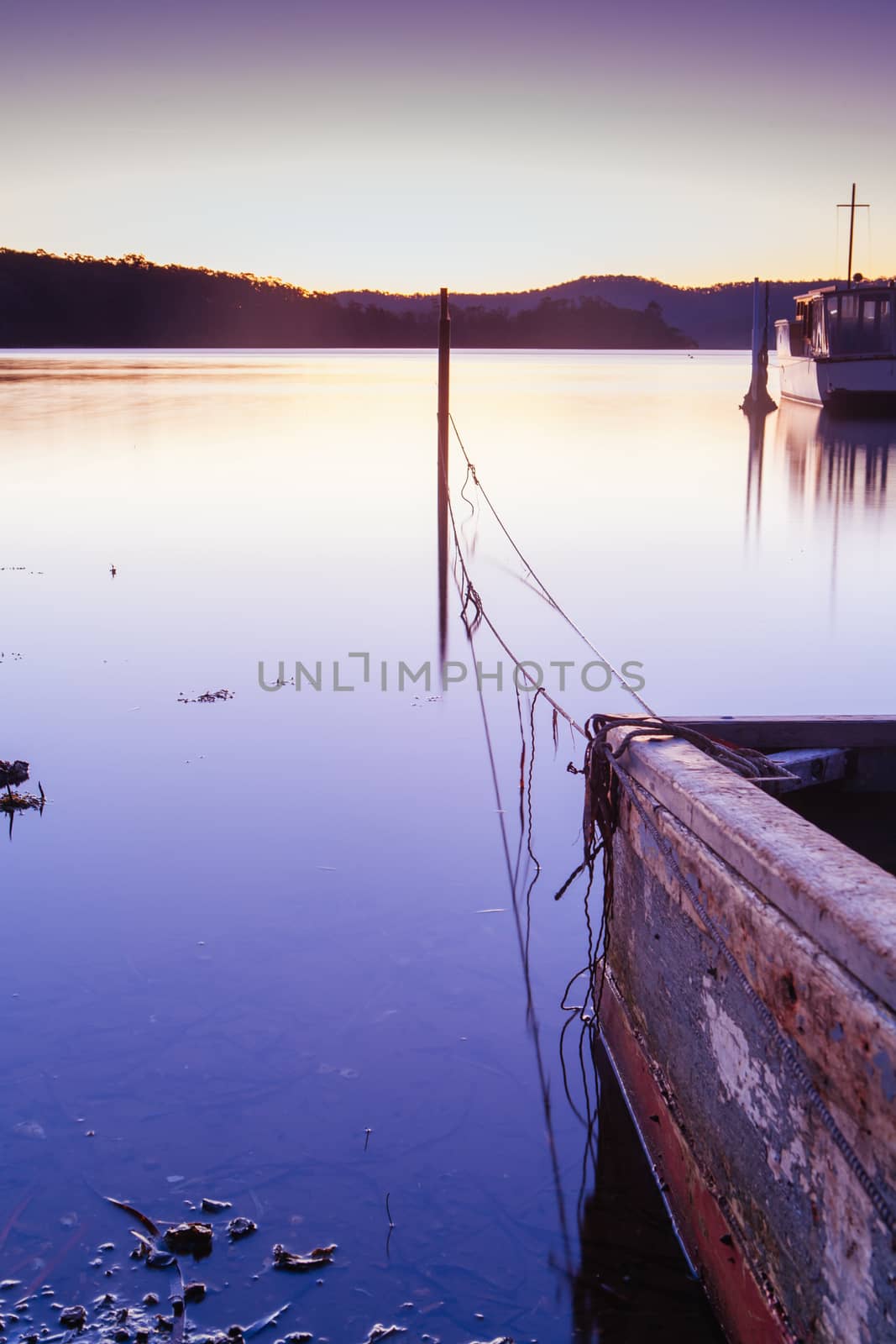 The idyllic setting across Wagonga Inlet and a disused boat at sunset in Narooma, NSW, Australia