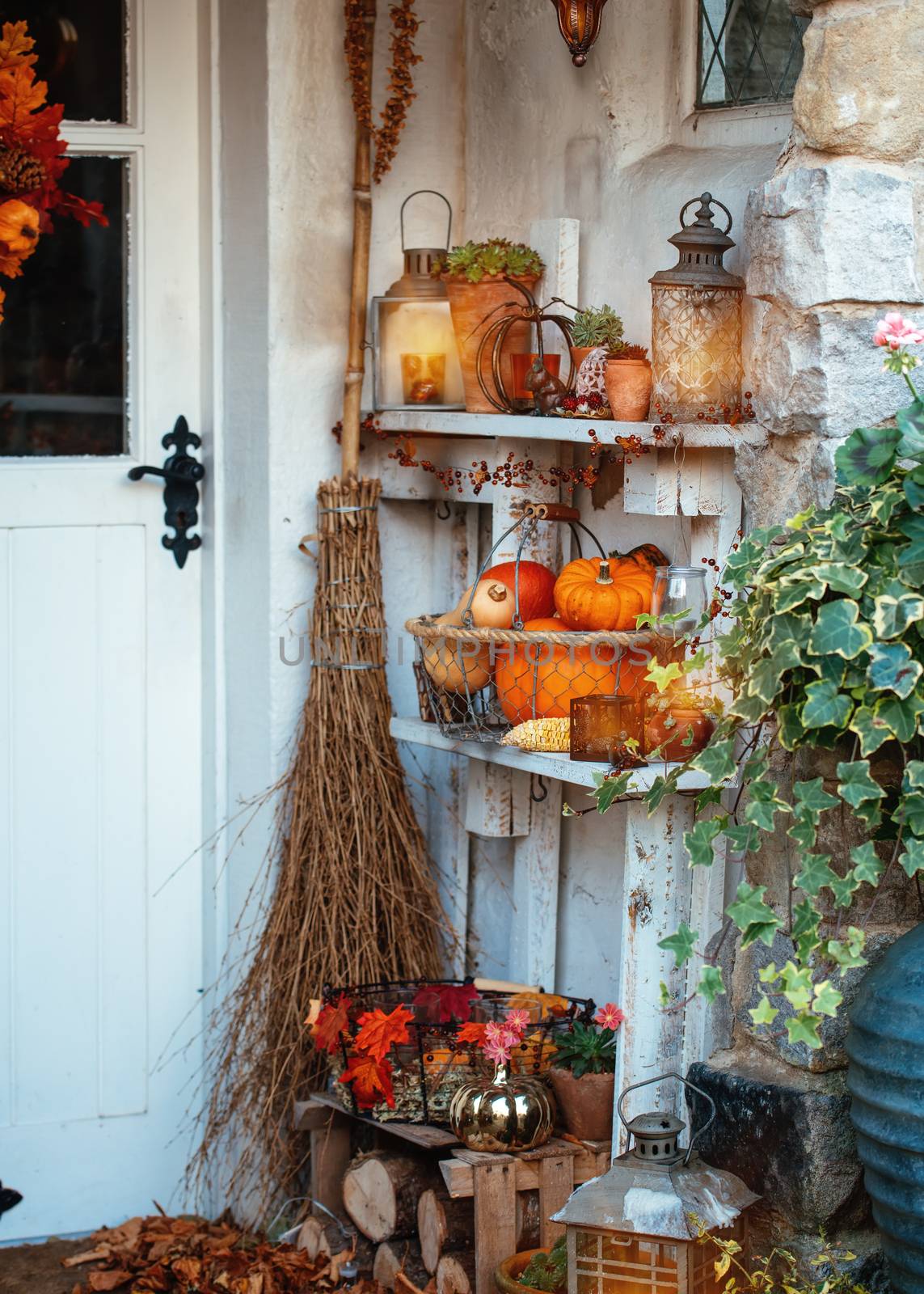 Halloween decoration lanterns, pumpkins, and broom in front of the house by Iryna_Melnyk