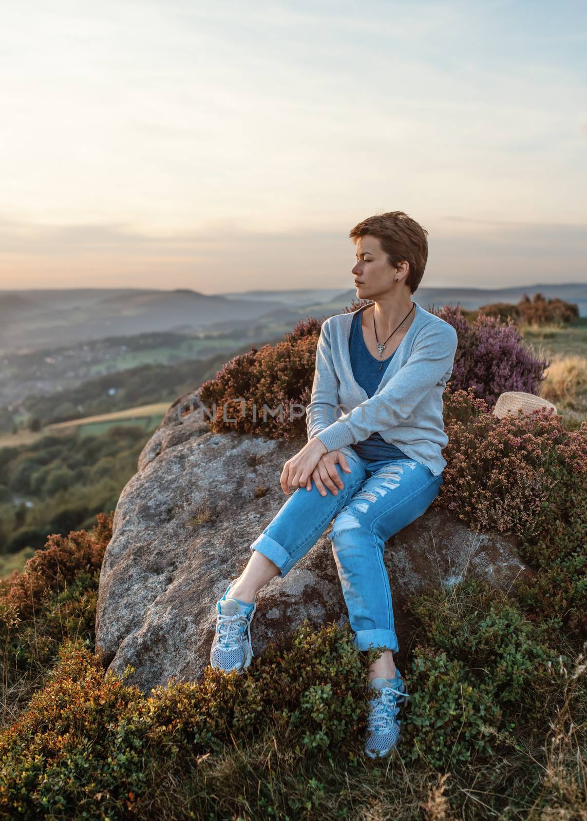 A woman sitting on top of hill against an amazing landscape in the autumn