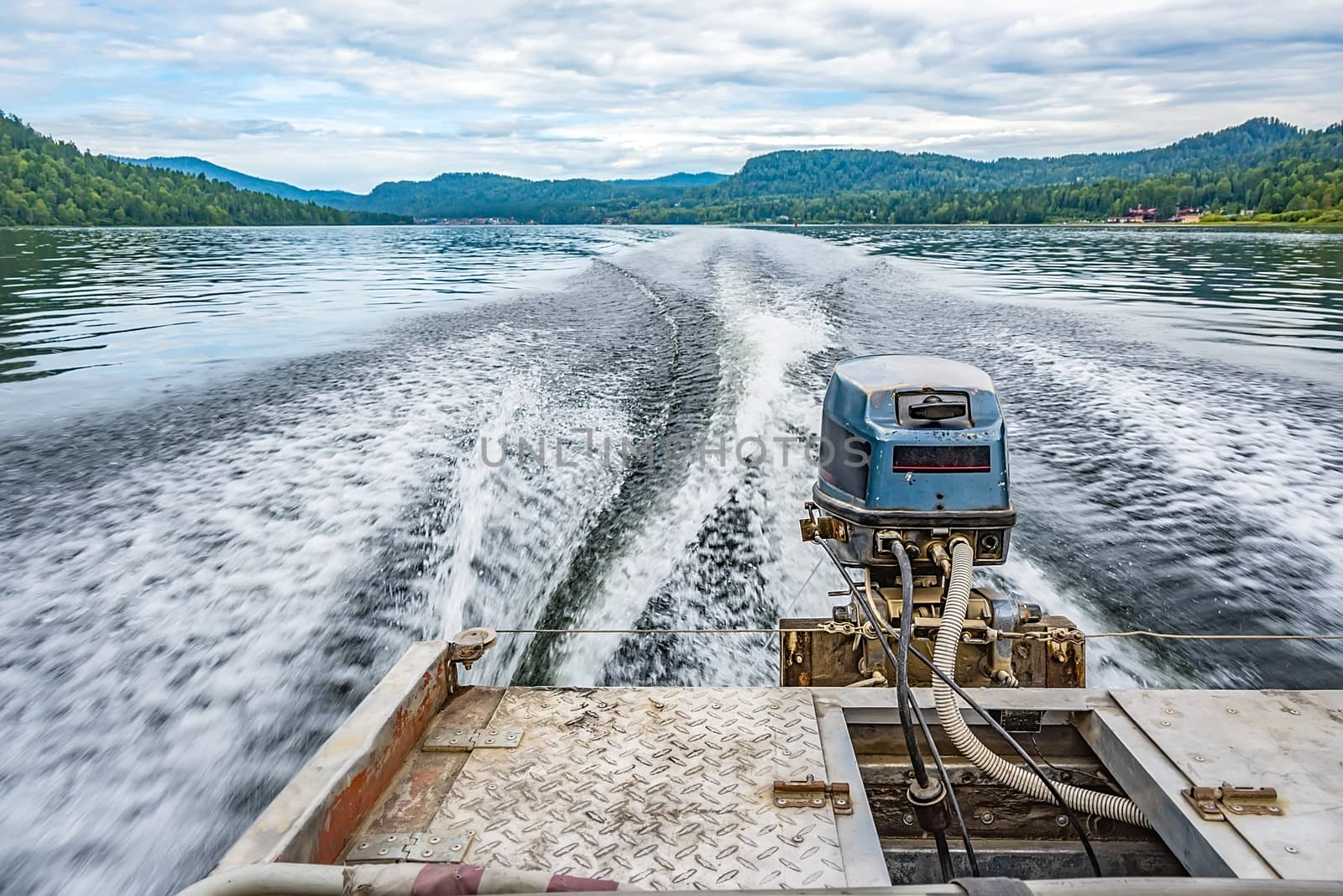 view of the engine on the motor boat from behind and the water trail with splashes and scenery on the big lake