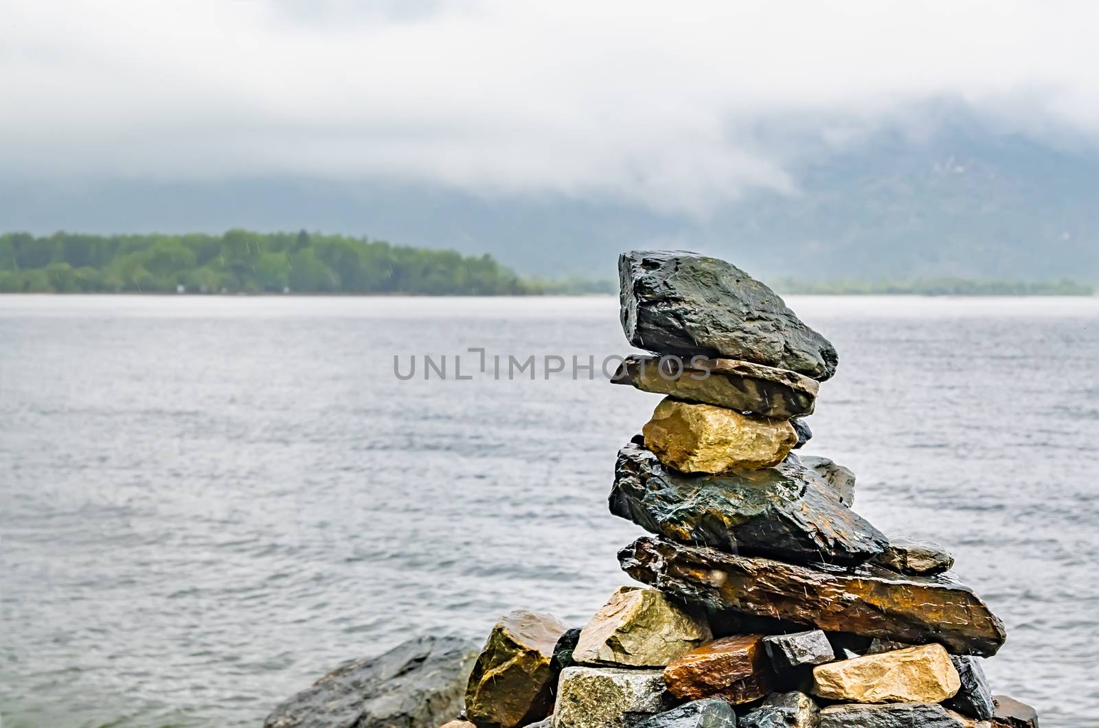 stones laid in the form of a pyramid lie on the shore of the lake by jk3030