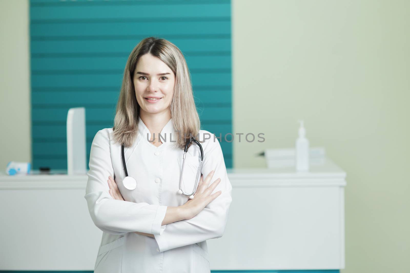 Smiling female doctor or nurse in medical uniform, stethoscope on the neck. In the hospital reception