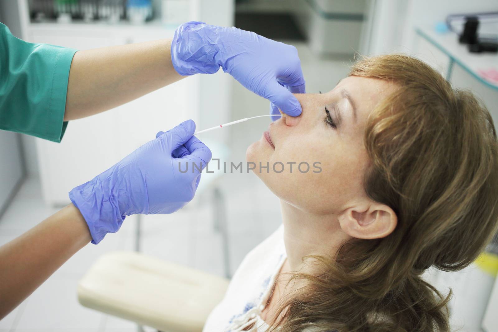 A nurse wearing a medical mask takes a swab from a patient's nose. by selinsmo