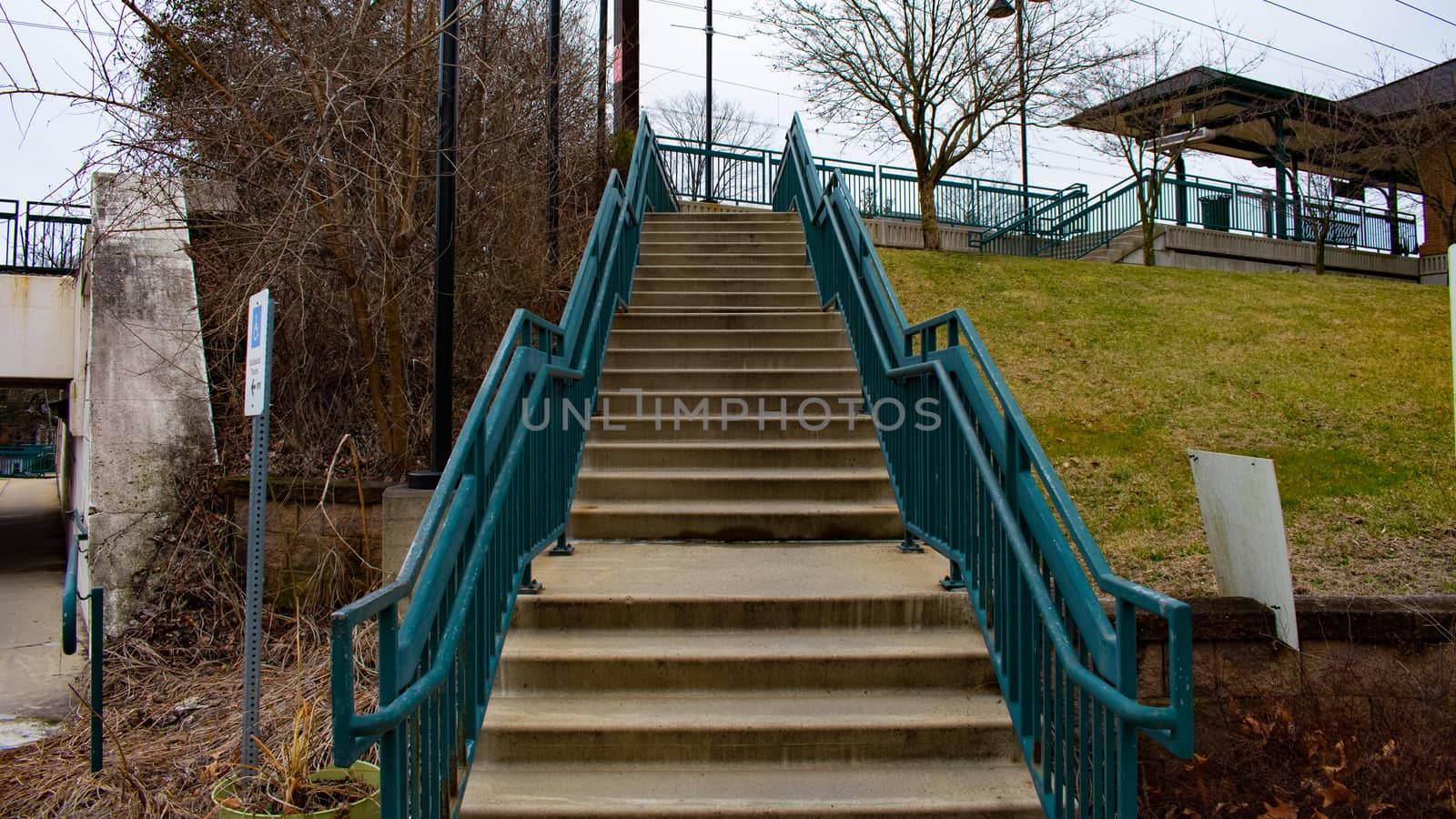 Concrete Steps Leading Up to a Train station With Blue Railings  by bju12290