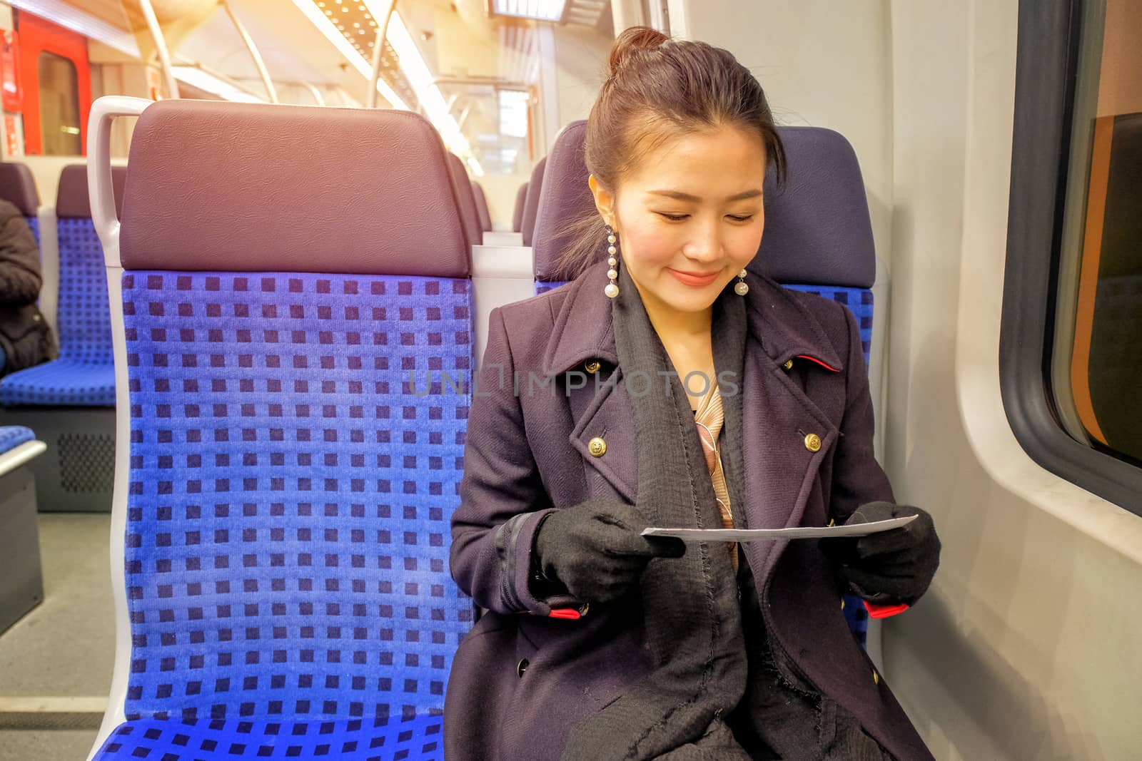 Young woman traveling looking ticket while sitting in the train.