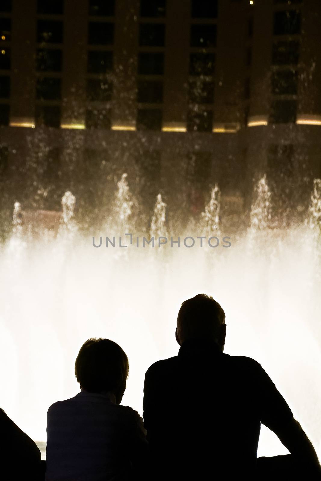 Night scene with silhouettes of people admiring the Bellagio fountains spectacle at Las Vegas