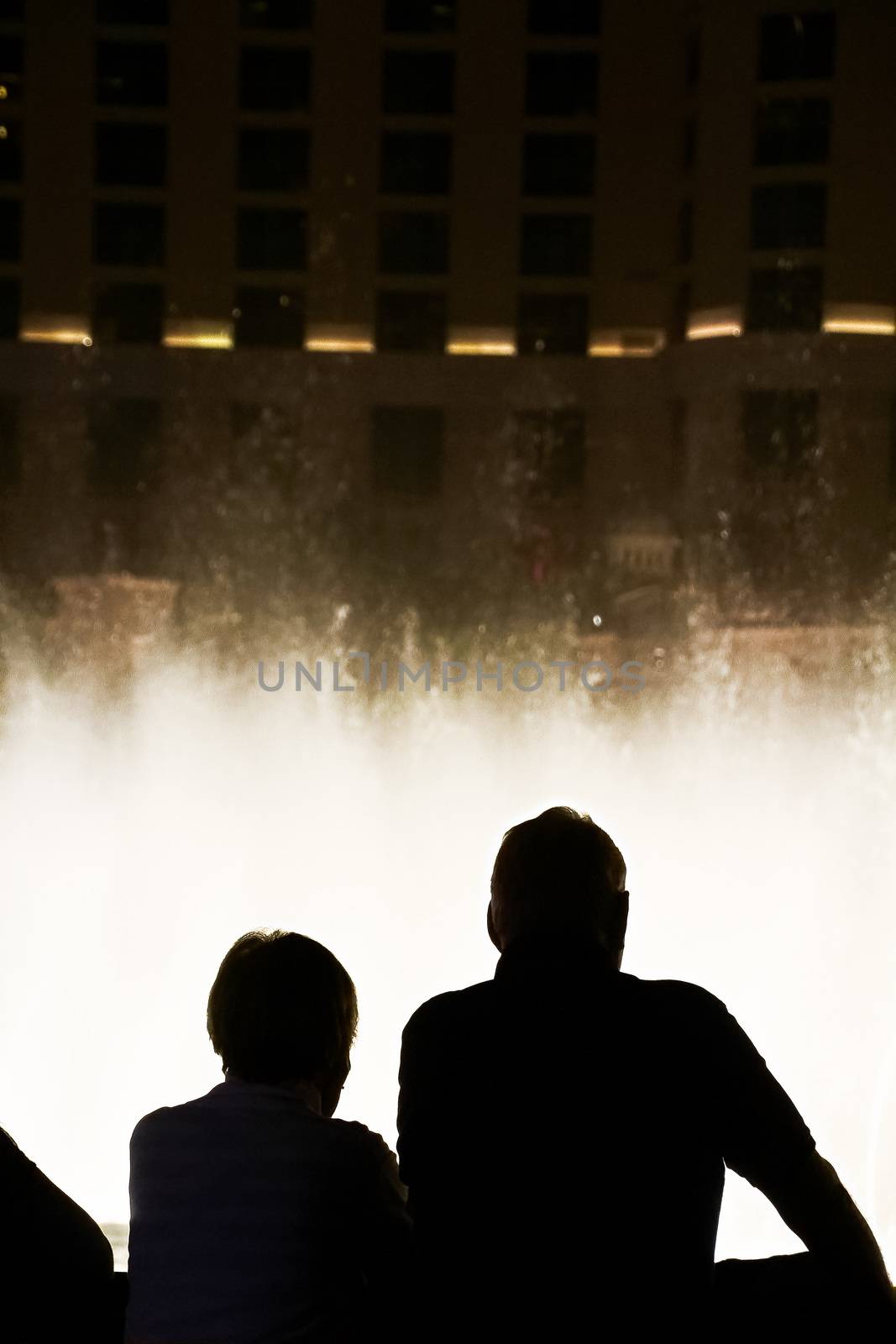 Night scene with silhouettes of people admiring the Bellagio fountains spectacle at Las Vegas