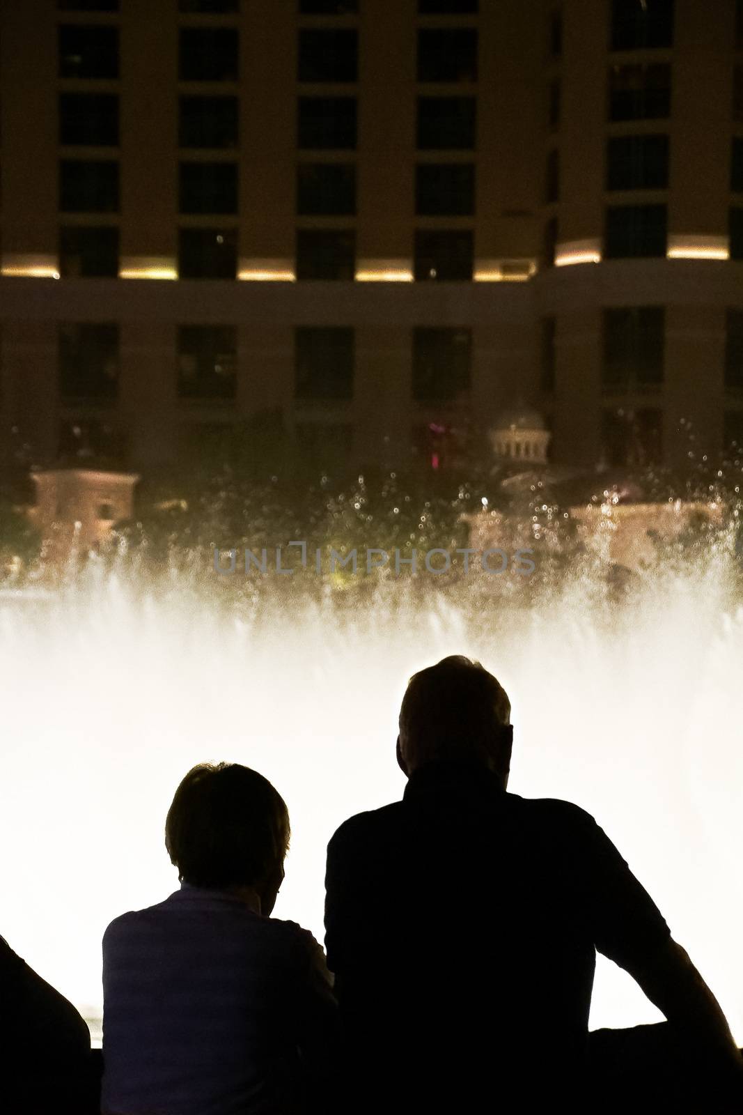 Night scene with silhouettes of people admiring the Bellagio fountains spectacle at Las Vegas by USA-TARO