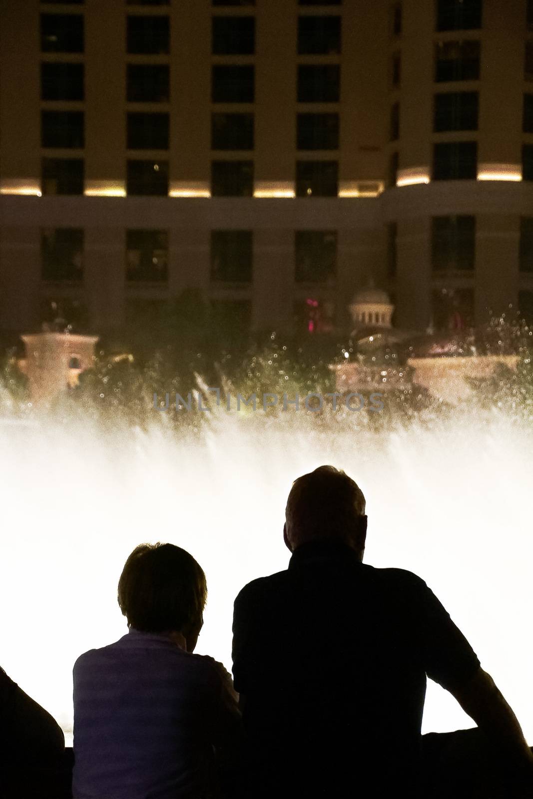 Night scene with silhouettes of people admiring the Bellagio fountains spectacle at Las Vegas