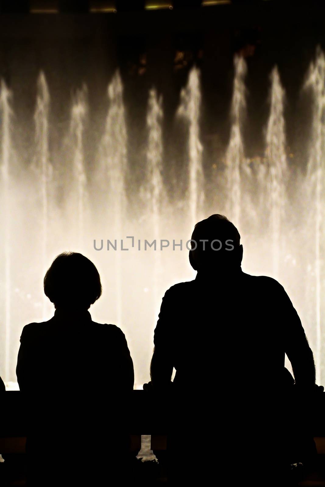 Night scene with silhouettes of people admiring the Bellagio fountains spectacle at Las Vegas