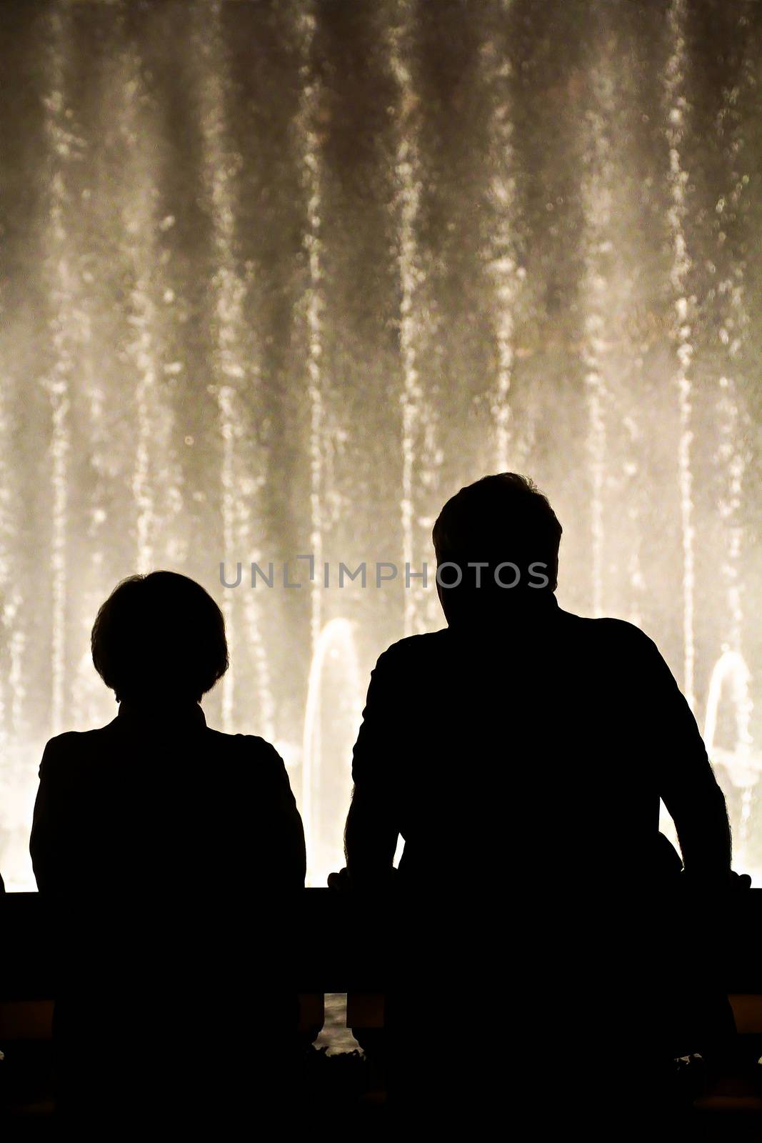 Night scene with silhouettes of people admiring the Bellagio fountains spectacle at Las Vegas