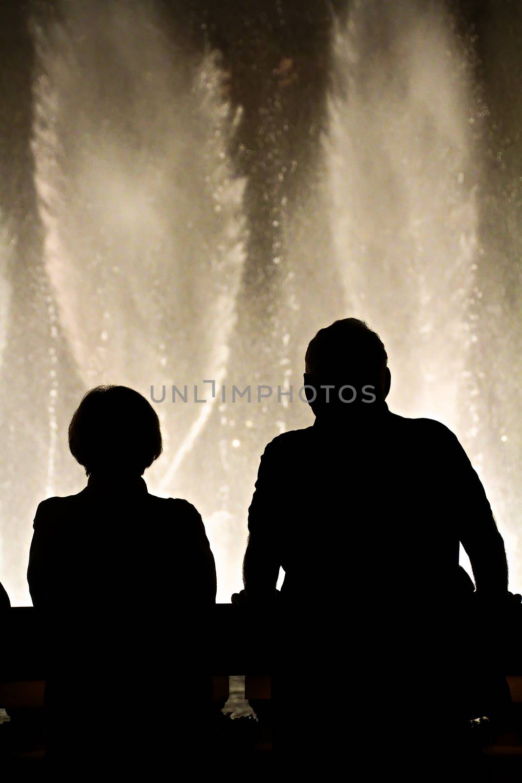 Night scene with silhouettes of people admiring the Bellagio fountains spectacle at Las Vegas