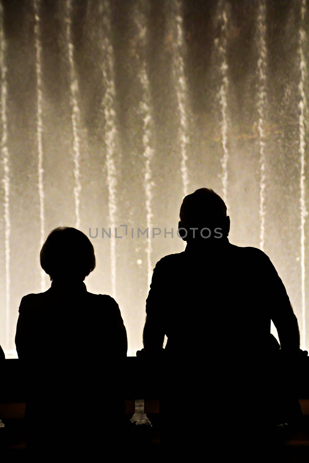 Night scene with silhouettes of people admiring the Bellagio fountains spectacle at Las Vegas