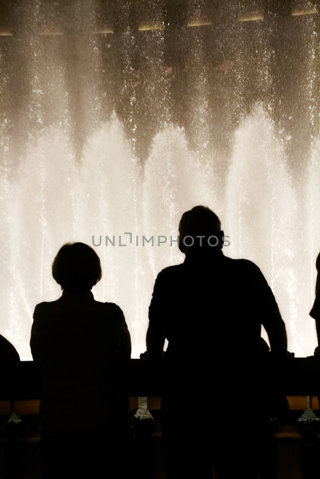 Night scene with silhouettes of people admiring the Bellagio fountains spectacle at Las Vegas