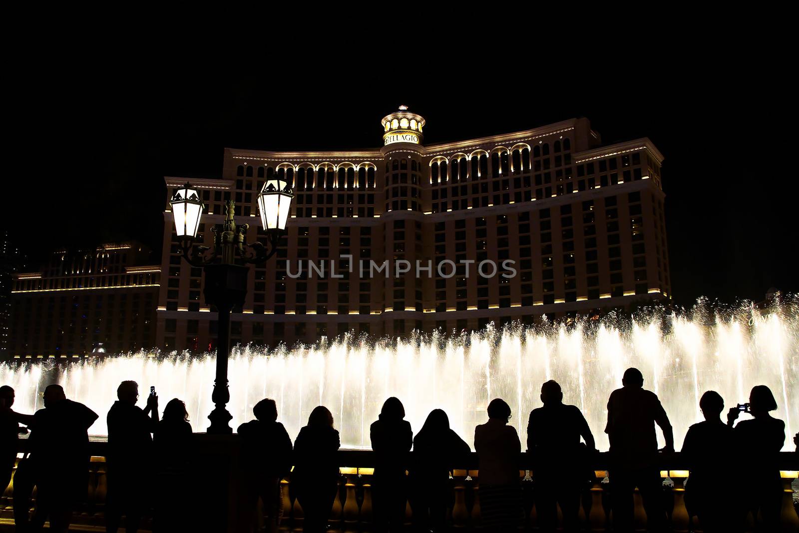 Night scene with silhouettes of people admiring the Bellagio fountains spectacle at Las Vegas by USA-TARO