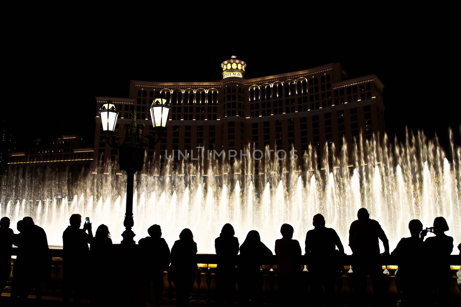 Night scene with silhouettes of people admiring the Bellagio fountains spectacle at Las Vegas by USA-TARO