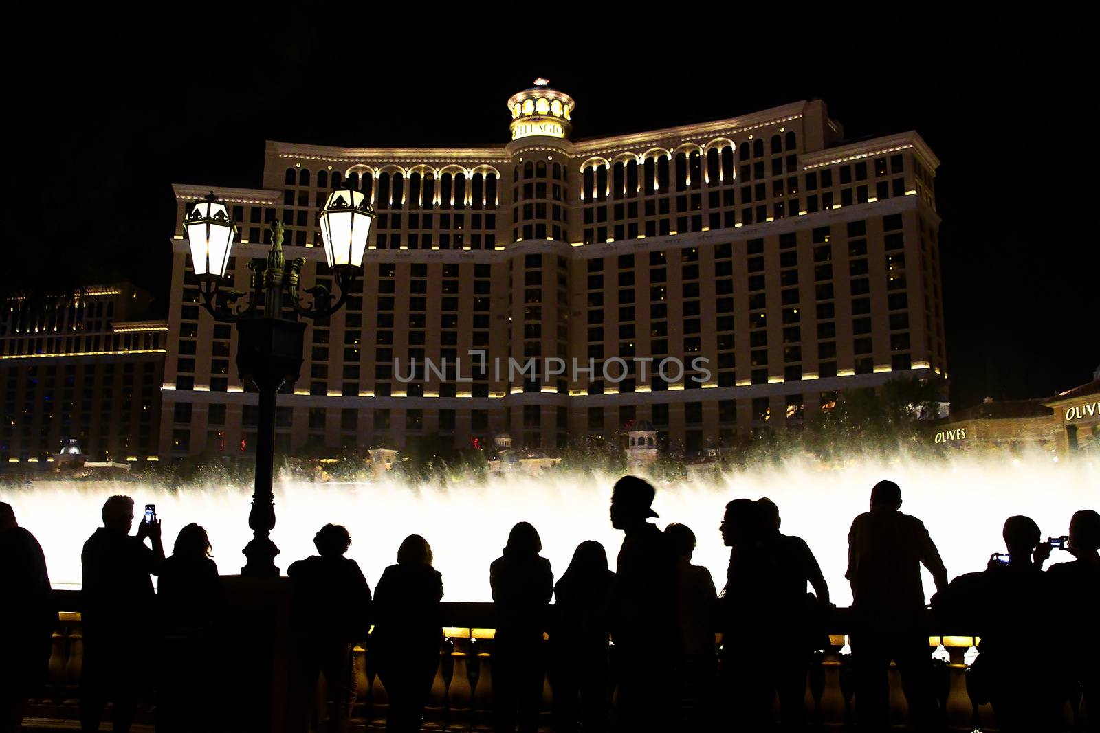 Night scene with silhouettes of people admiring the Bellagio fountains spectacle at Las Vegas by USA-TARO